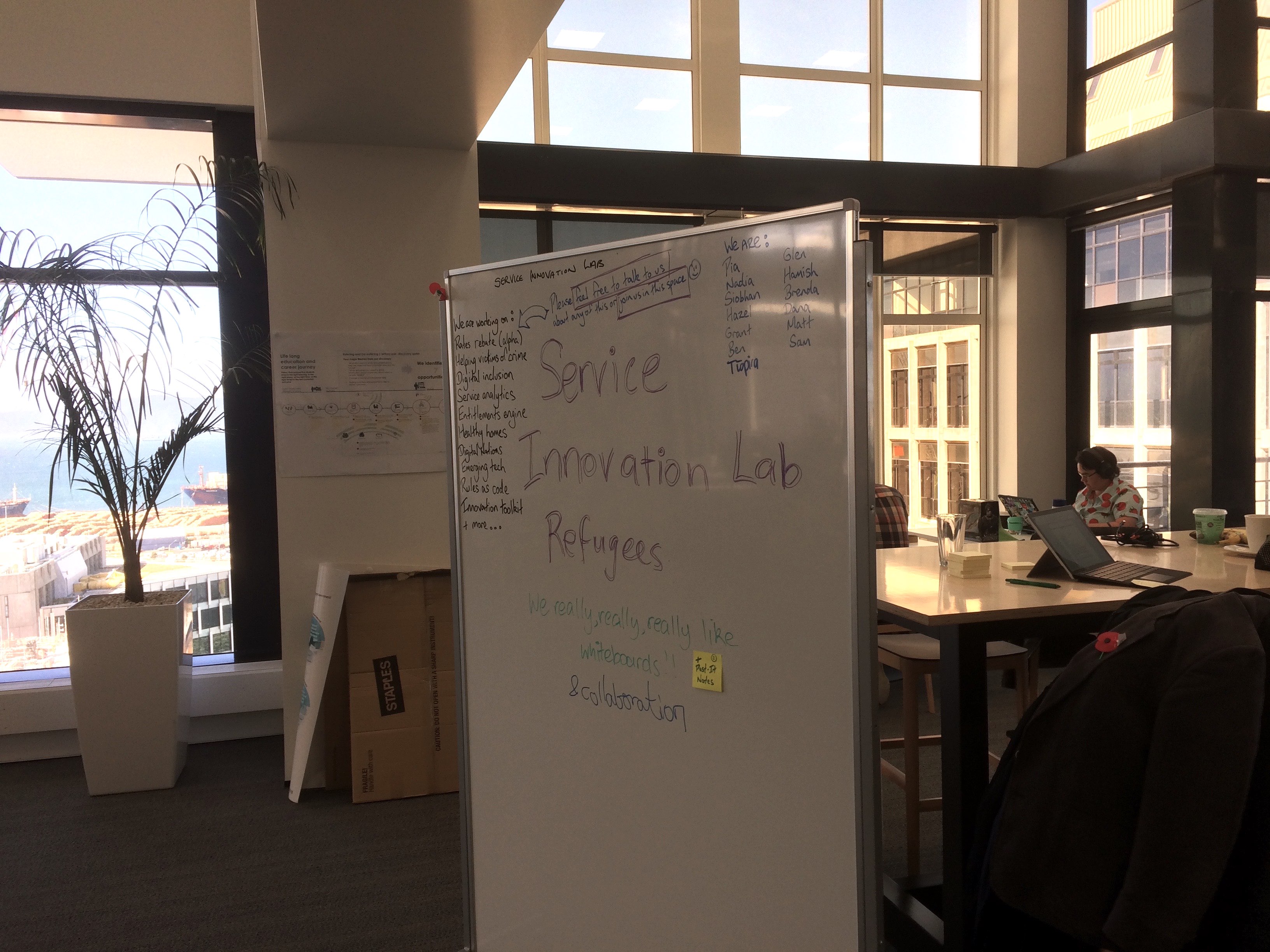 Two persons work behind a whiteboard where “Service Innovation Lab Refugees” can be read.